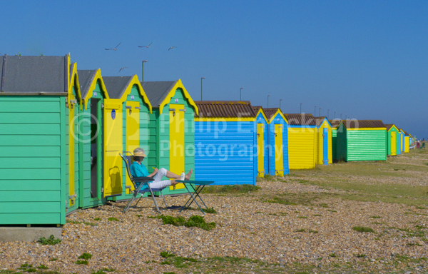 Woman sitting by beach huts, Littlehampton ,England