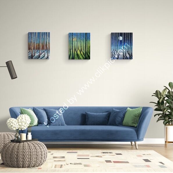 A row of three colourful abstracted paintings displayed over a blue sofa