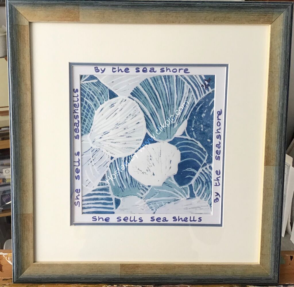 A linocut print showing seashells, teal blue and navy, words round mount, framed