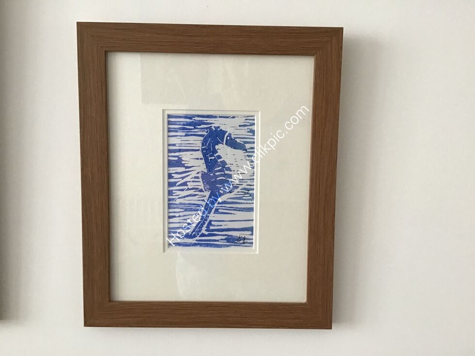 A linocut of a seahorse, printed in blue on white, framed