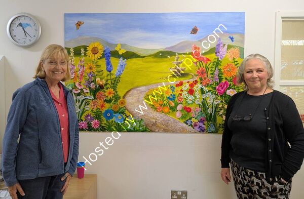 Teresa and Toots, who created the collage using flowers and butterflies painted by members of the Art Society.