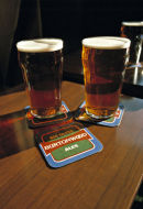 Two pints of bitter on pub table.