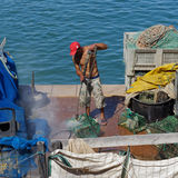 Man with red cap washing lobster pots, Cascais
