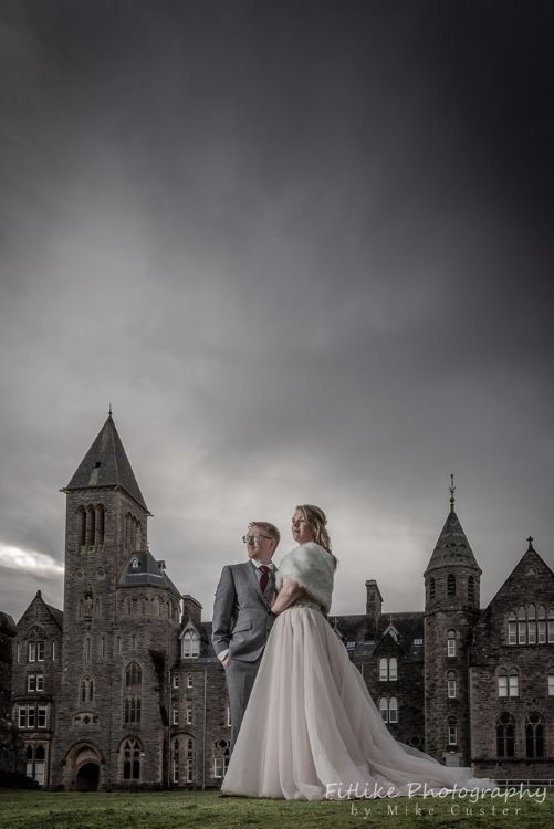 Elgin Wedding Photographer. Dark and moody on a rainy day.Bride & Groom in romantic pose outside an old abbey.