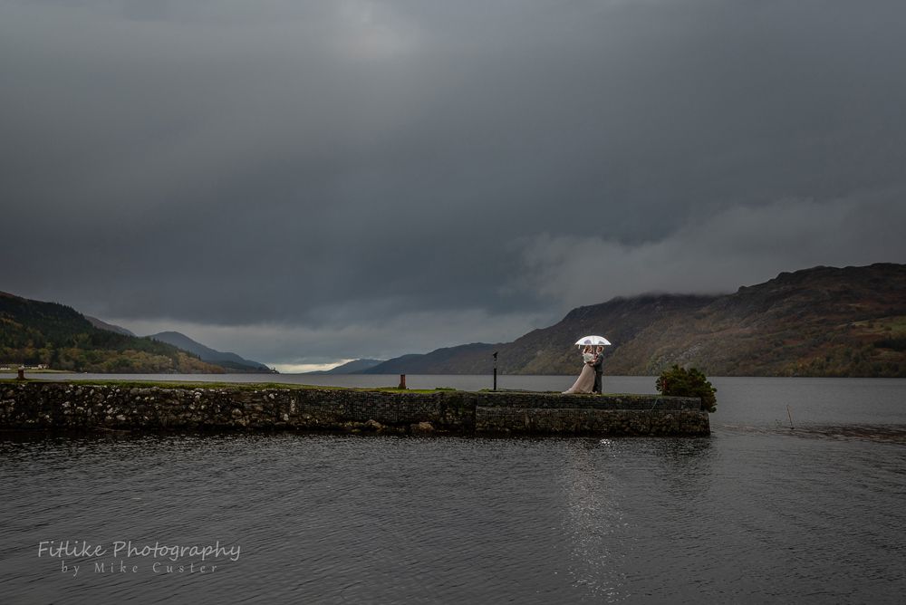Bride & Groom in a romantic pose on a jetty looking up Loch Ness from Fort Augustus.