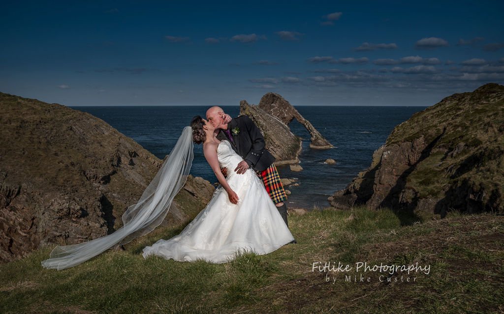 Bride and Groom in Romantic pose. Lit by off camera flash. Posed to replicate the angles of Bow Fiddle Rock, Portknockie, Moray, Scotland.
