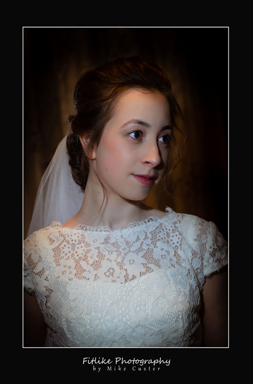 The bride is posed in a darkened room and lit to give a dramatic look.