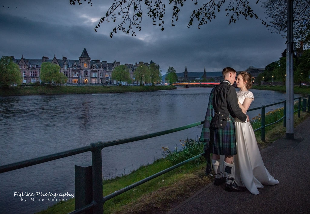 Bride & Groom holding hands in romantic pose at the river side. Taken at twilight
