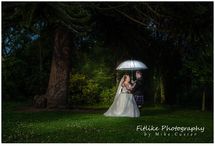 Inverness-Wedding-Photographers-01 The bride and groom posed near a dark set of trees. Holding a white umbrella they were lit from behind and the front with off camera flash.