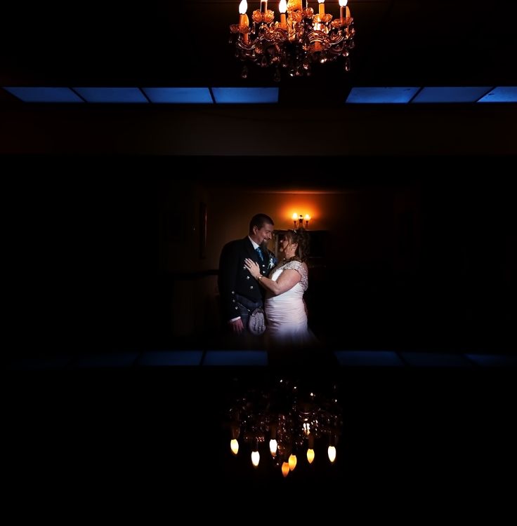 Bride and Groom in Romantic pose. Lit by off camera flash. The reflection created in camera using a phone