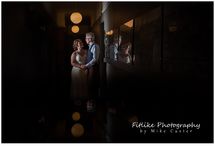 Perthshire-Wedding-Photographers-01 A wedding photograph of the couple posed in a hallway. With light fittings reflected below and the couple reflected in a picture frame.