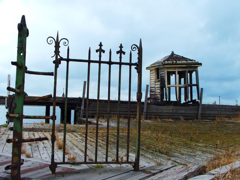 Rusty old gate and burnt out hut