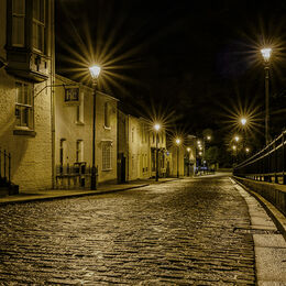 WET COBBLES: Very good street scene at night. Lights illuminating walls and fence nicely. Street lights not too overblown with effective star shapes. Nicely led into the picture and held there. Good image.