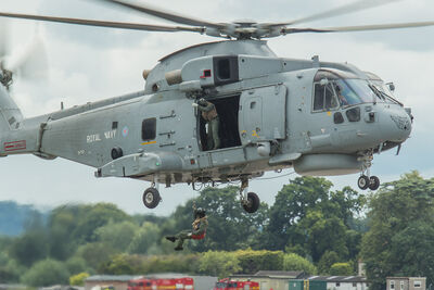 A RoyalNavy Merlin hovering with a man on the winch. Agusta Merlin hovering with winchman
