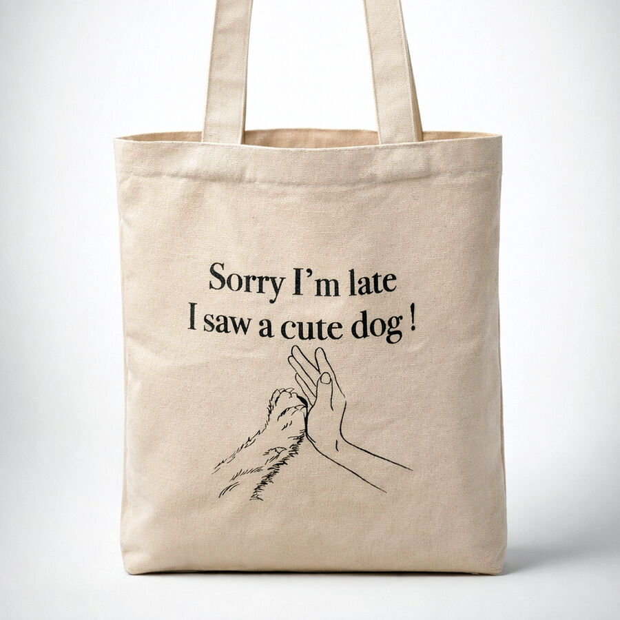 natural canvas tote bag with the print of a hand high fiving a dog's paw and the message " Sorry I'm late I saw a cute dog!"