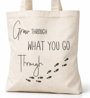 A natural coloured canvas tote bag with a printed message saying "Grow Through What You Go Through" and some footsteps.