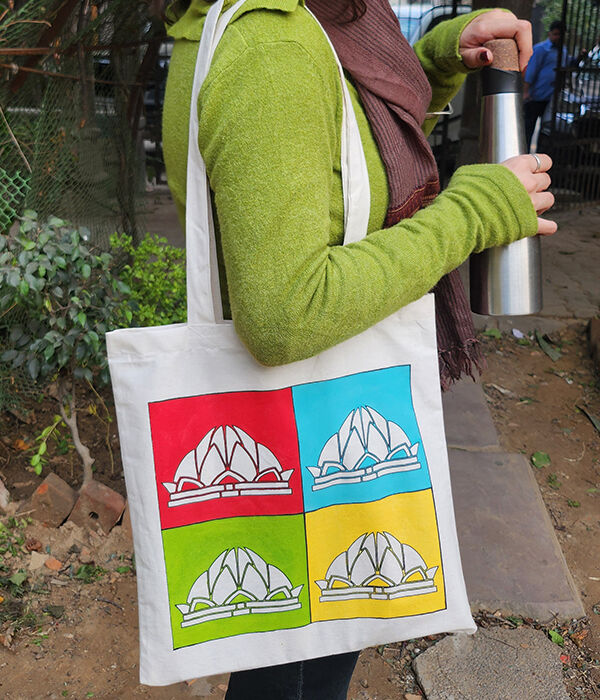 A woman carrying a tote bag with a brightly coloured panel of printing depicting the lotus temple on the front.