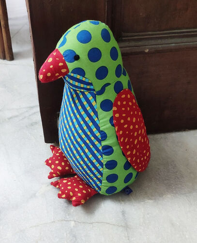 Brightly coloured cotton print penguin doorstop sitting before an open door