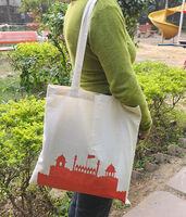 A woman carrying a cotton tote bag with a print of the red fort on the front.