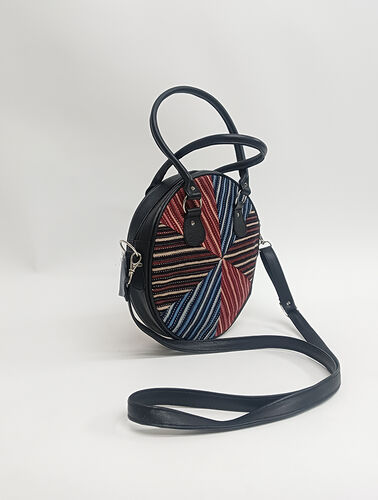 Round leather and patchwork bag. The straps and sides are blck leather and the front and back are made of pieces of fred, blue and rust handloom cotton