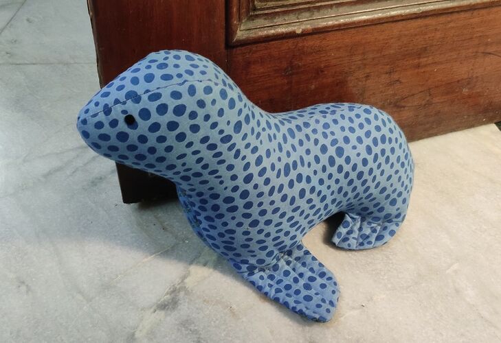 Blue dotted cloth seal doorstop resting infront of an open door