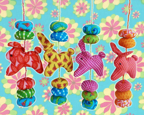 Four different cotton mobiles with two discs, one bunny and three discs hanging on a beaded string.