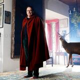 portrait of a man wearing a cloak, inside a country house, with a deer behind him