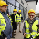 Smiling people on a building site visit, everyone wearing yellow hard hats, business photography by Thousand Word Media, Gloucestershire and South West.