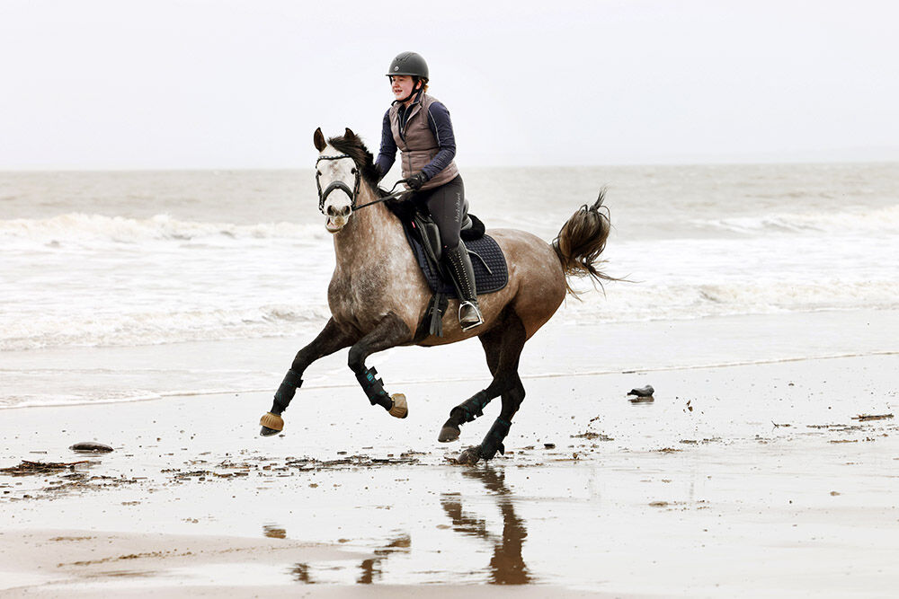 A horse being ridden through the sea, Cotswolds equestrian photography by Thousand Word Media, Gloucestershire.