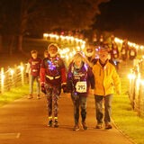 Charity walkers at night on a lit up long driveway event photography by Thousand Word Media Cheltenham.