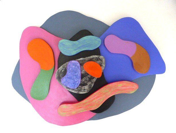 curved wooden pieces in different colours on a mid-grey irregular rounded base