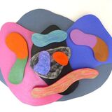 curved wooden pieces in different colours on a mid-grey irregular rounded base