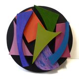 Eight different shaped and coloured pieces on a black roundel.