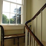 stairwell and bannisters and window in Bath with walls painted in Soft Angelica by Designers Guild