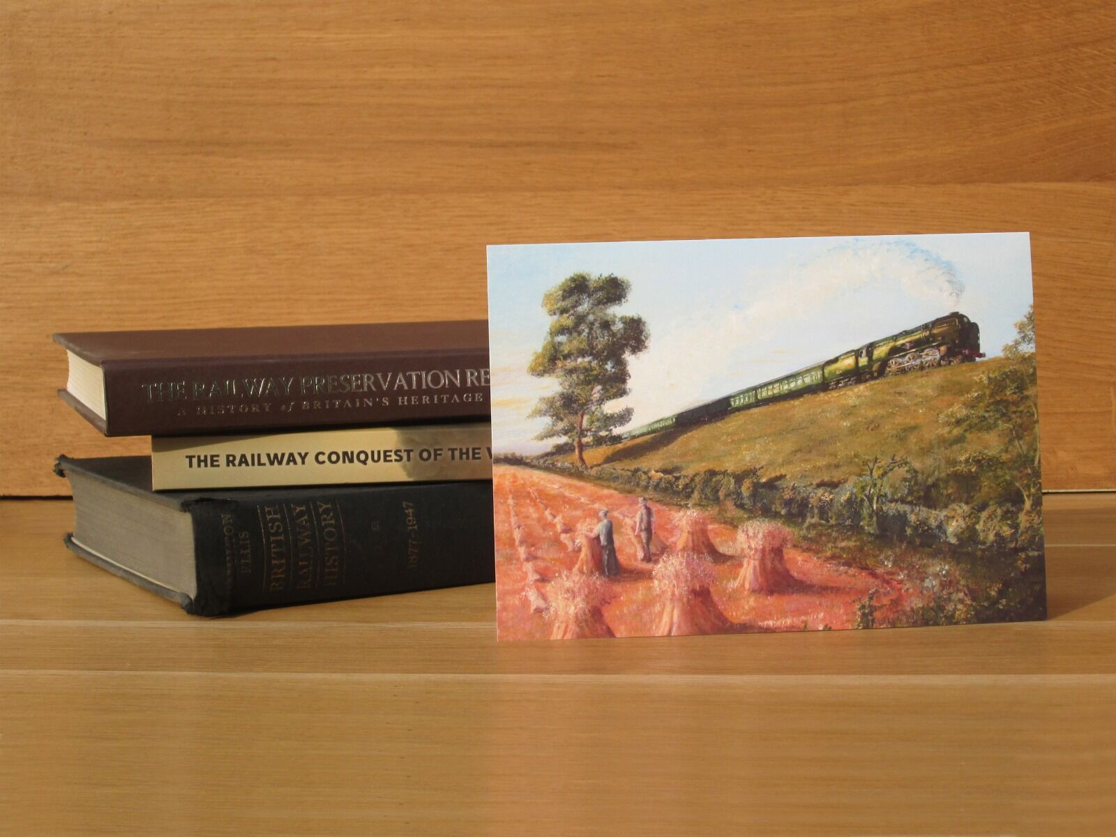 Painting of a Merchant Navy Loco passing farm workers stooking corn