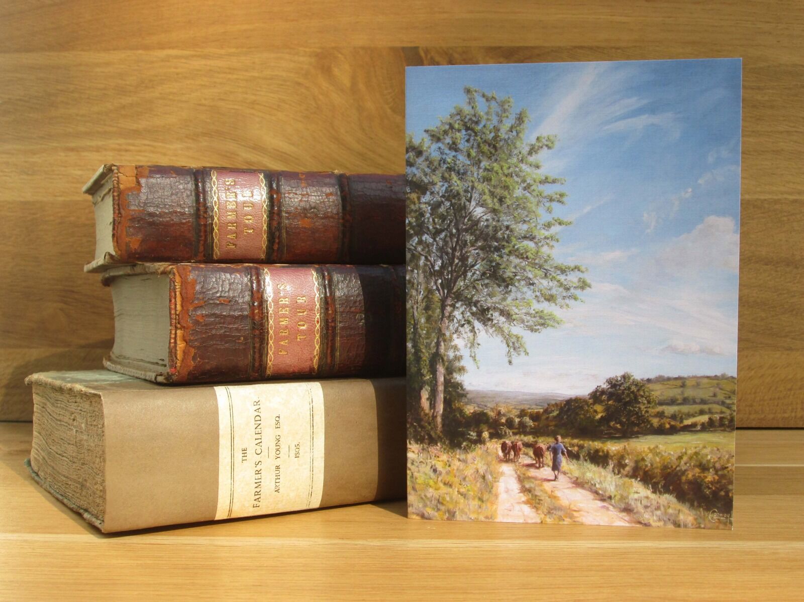 Painting of springtime view down a valley with woman herding cattle down a lane.