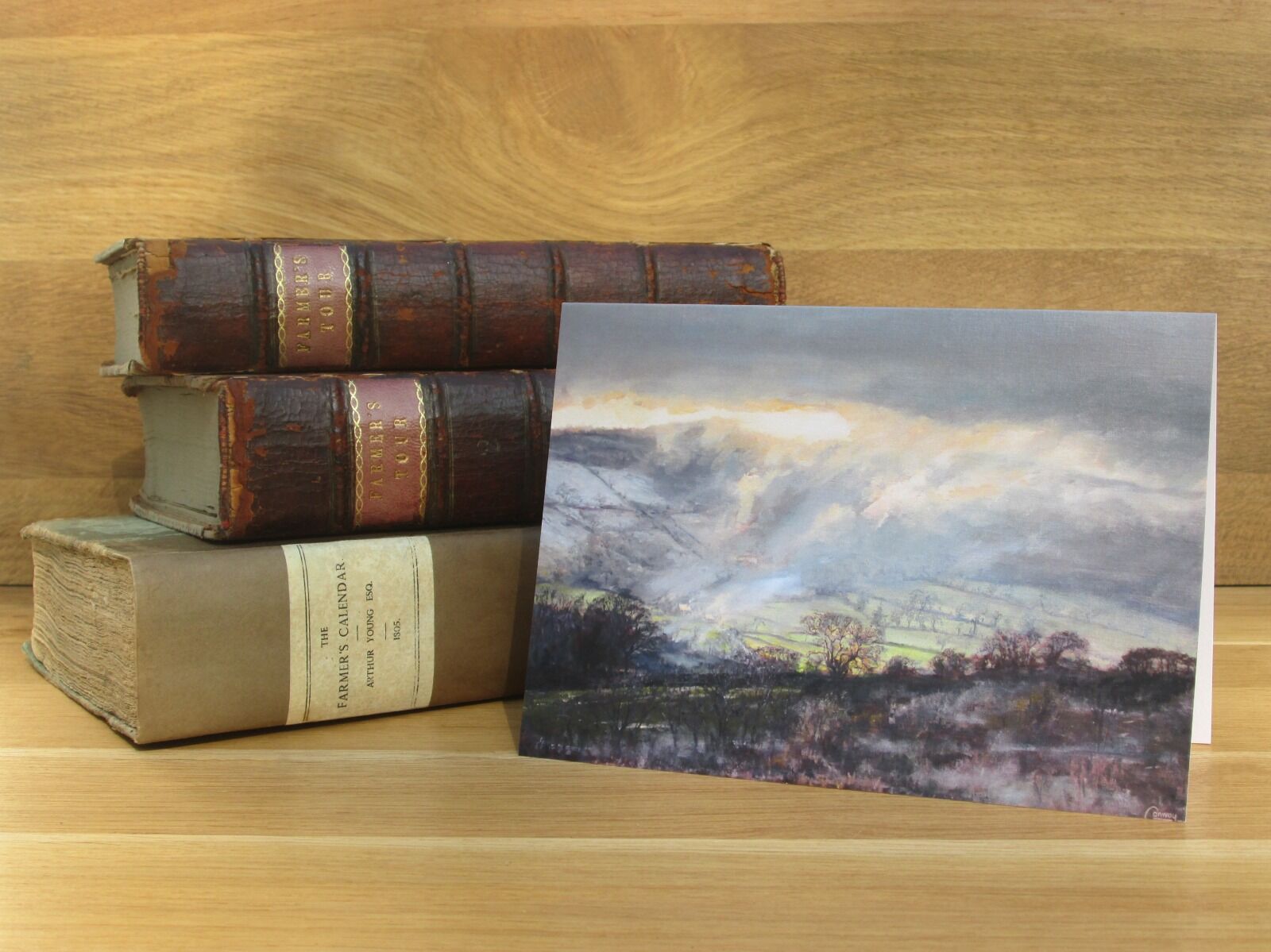 Painting of sunlight shing through cloud over a wintery landscape.