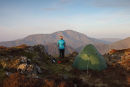 04D-5131 Hill Walker with Tent on Fleetwith Pike and the View Towards the Mountain of Pillar (Centre) in Early Morning Light Lake District Cumbria UK