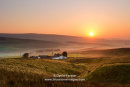 The North Pennine farm of Peghorn Lodge illuminated by the rising sun as mist rises in the valley below, Upper Teesdale, County Durham UK