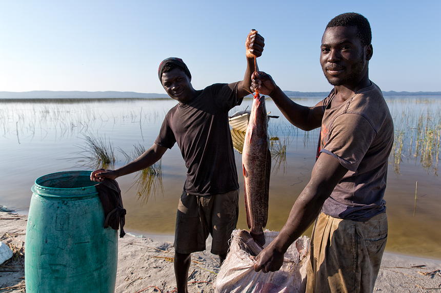 Proud fishermen showing off their catch - a large catfish - before heading to the market.