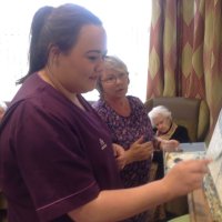 Primrose Court staff member having a go at painting using a spoon