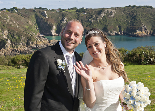 Waving to their guests in front of a stunning clifftop backdrop.