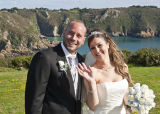 Waving to their guests in front of a stunning clifftop backdrop.