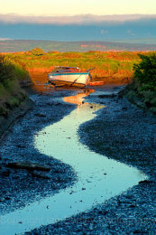 Lone yacht at low tide on Penngton Marsh, Lymington, Hampshire, England