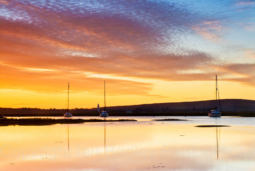 Dawn over the Isle of Wight reflected in the water off Keyhaven with moored yachts, Hampshire, England