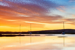 Dawn over the Isle of Wight reflected in the water off Keyhaven with moored yachts, Hampshire, England