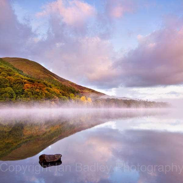 Still misty waters of Loweswater with trees in autumn colour, Lake District National Park, Cumbria, England