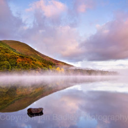 Still misty waters of Loweswater with trees in autumn colour, Lake District National Park, Cumbria, England
