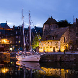 A classic sailing boat moored in the old port at Honfleur, France, at night