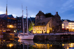 A classic sailing boat moored in the old port at Honfleur, France, at night